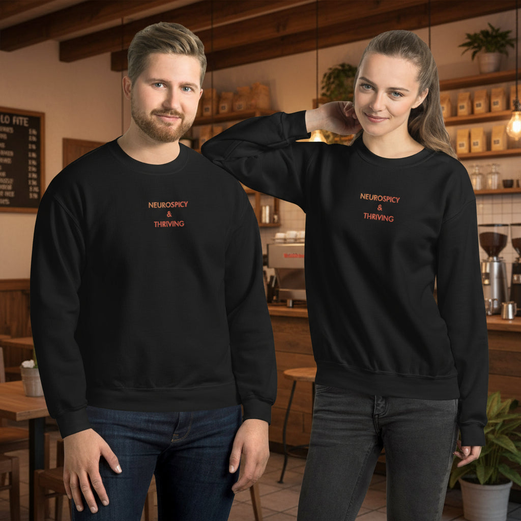 Man and Woman wearing Neurospicy and Thriving embroidered sweatshirt by Nyxhera Creations, black Gildan crewneck with red-to-orange gradient centre-chest embroidery