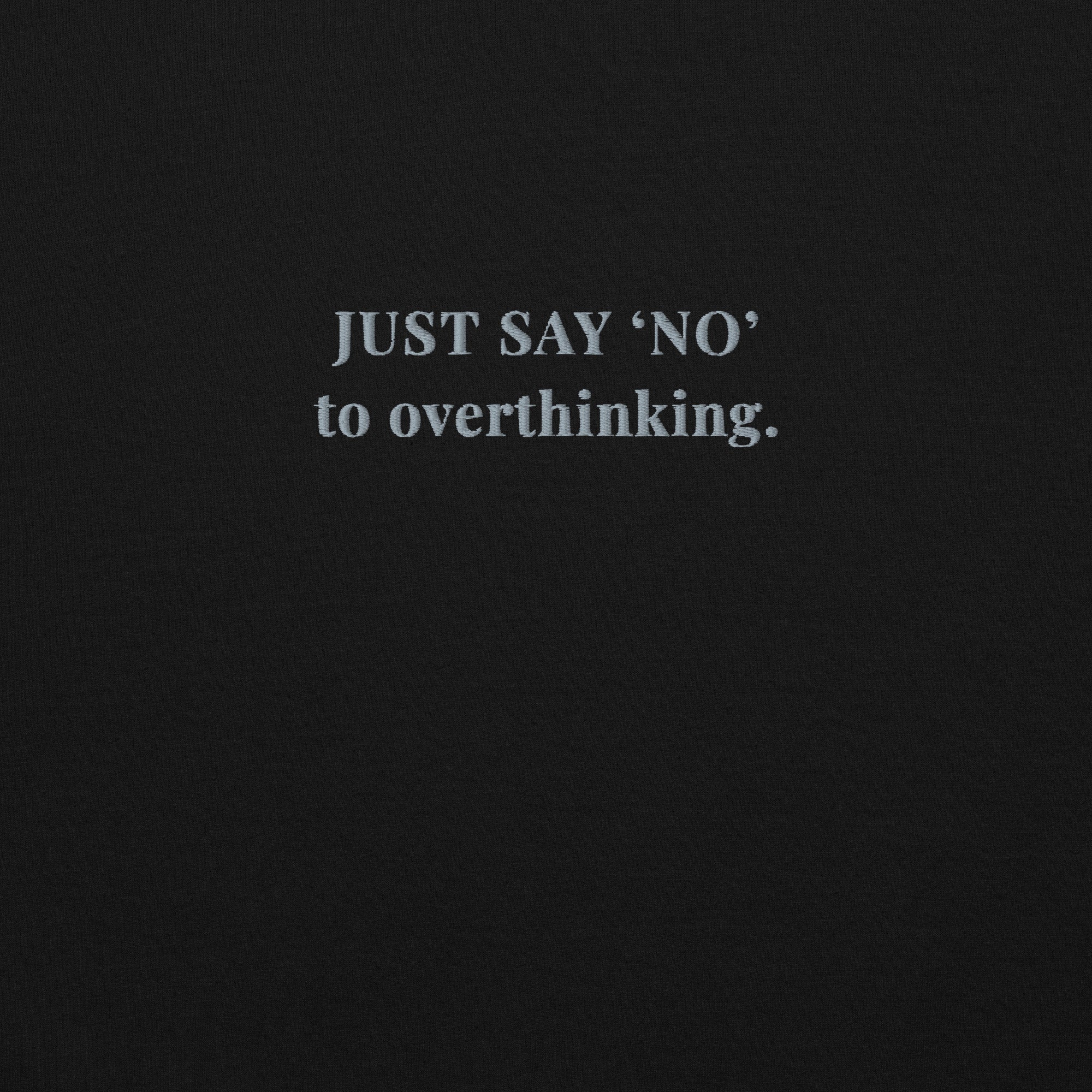 close up of embroidered motivational quote 'JUST SAY 'NO' to overthinking.' on a black sweatshirt