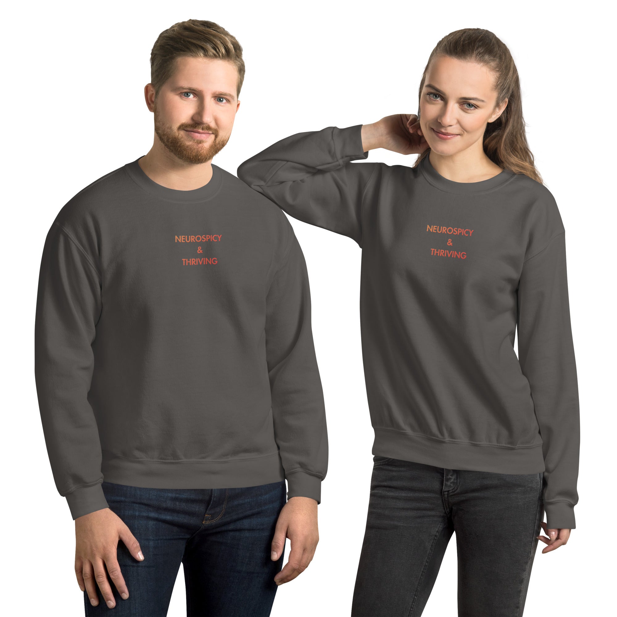 man and woman wearing Neurospicy and Thriving embroidered sweatshirt by Nyxhera Creations, charcoal Gildan crewneck with red-to-orange gradient centre-chest embroidery