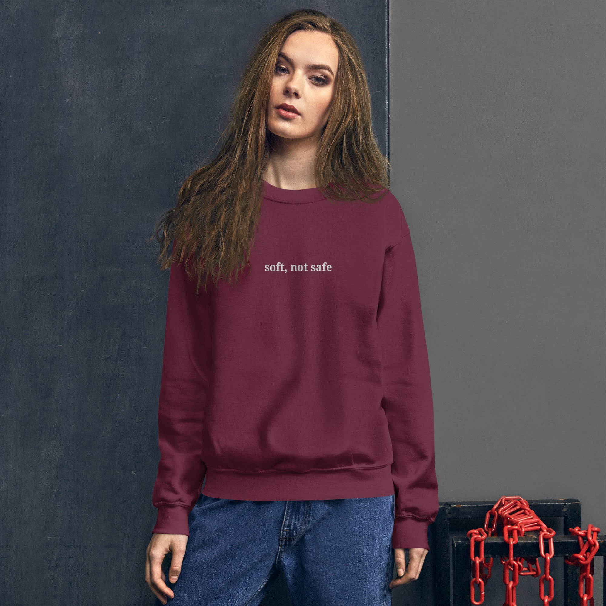 woman wearing Soft, Not Safe embroidered sweatshirt by Nyxhera Creations, minimalist design in maroon