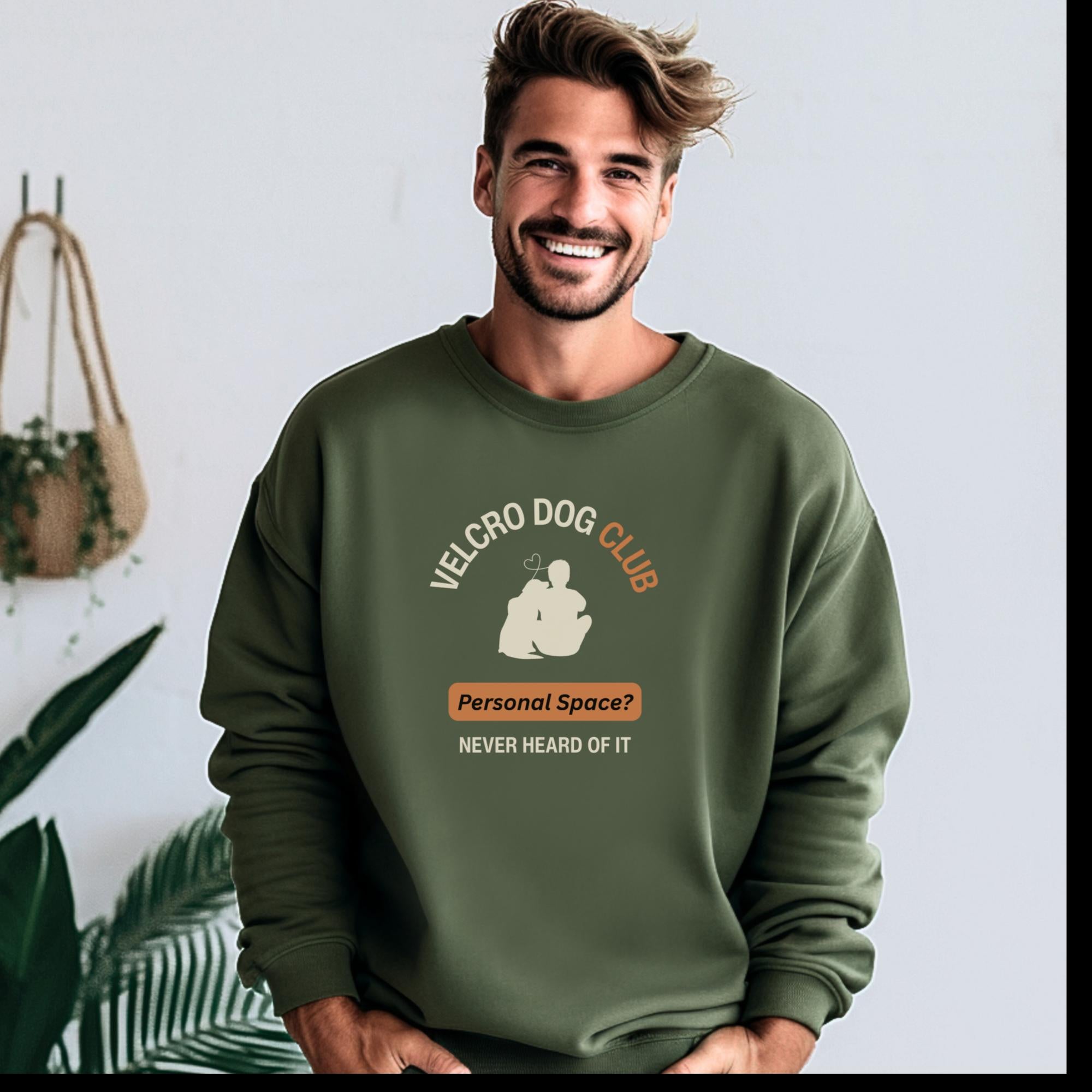 Man wearing a green sweatshirt with 'Velcro Dog Club' text and graphic, standing indoors.