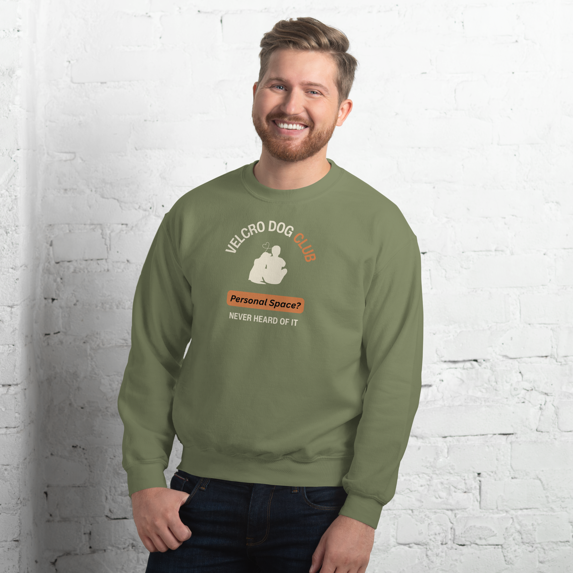 Man wearing a green sweatshirt with a graphic design against a white brick wall.