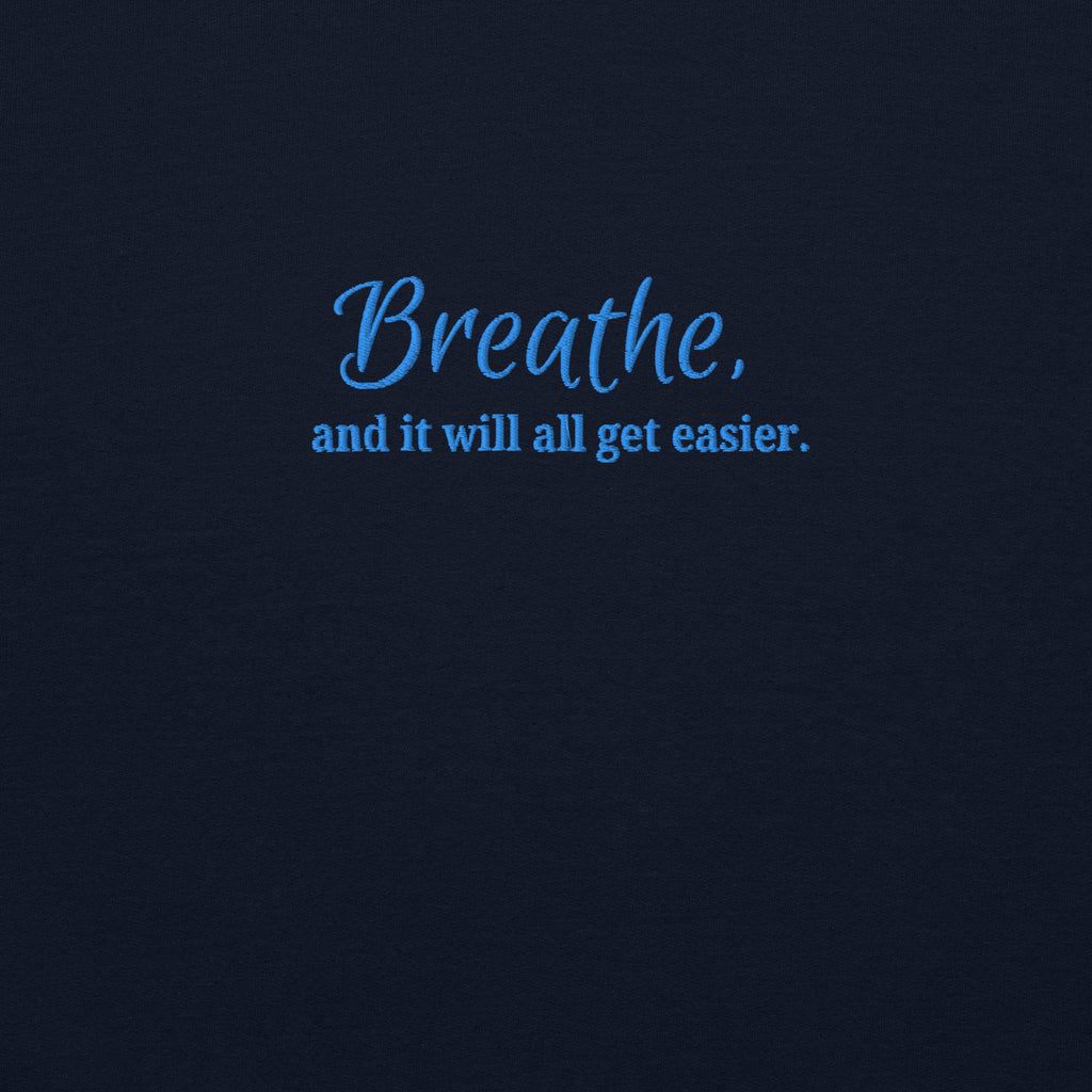 close up of embroidered motivational quote 'Breathe, and it will all get easier.' in blue text on a navy sweatshirt