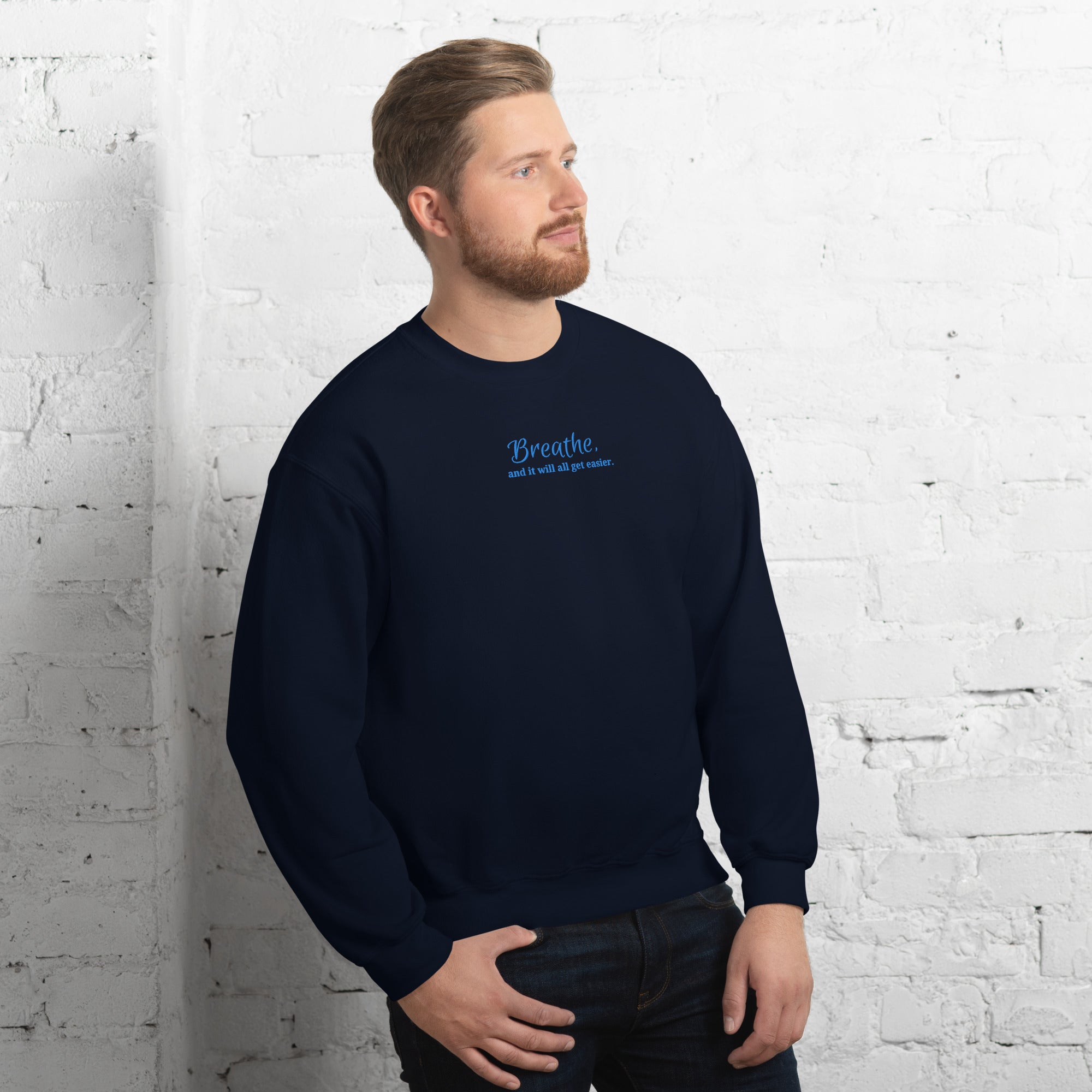 Unisex embroidered sweatshirt in navy featuring quote “Breathe and It Will All Get Easier” stitched in calming blue thread, modelled by a man
