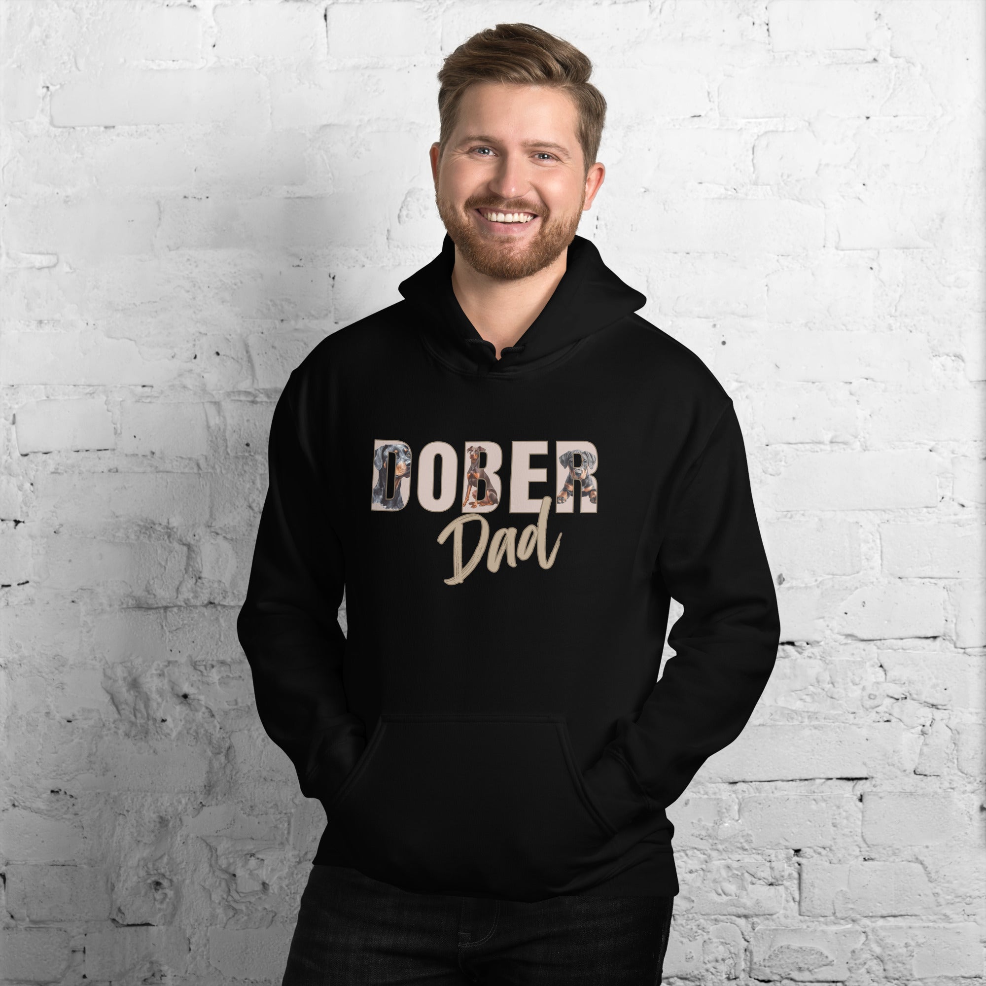 Man wearing a black hoodie with 'DOBER Dad' text against a white brick wall.