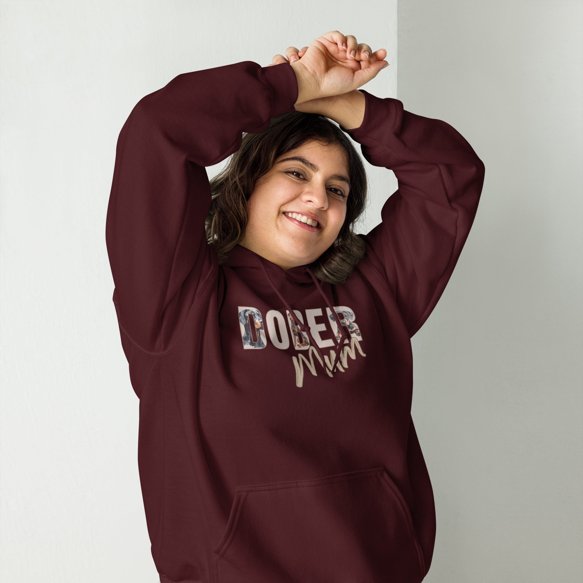 Person wearing a maroon hoodie with 'DOBER Mum' text, standing against a plain background