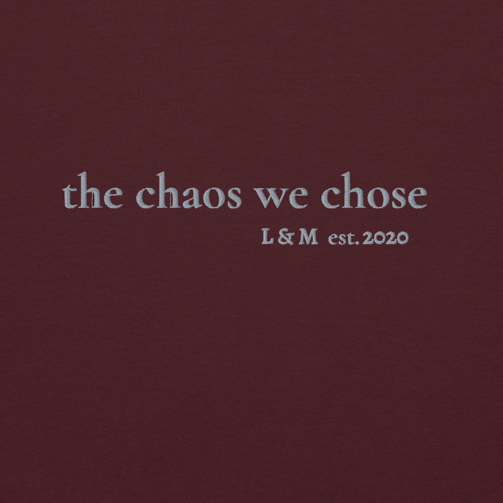 Close-up of grey thread embroidery reading ‘The Chaos We Chose est. [year]’ with personalised initials, premium stitching detail on cotton hoodie.