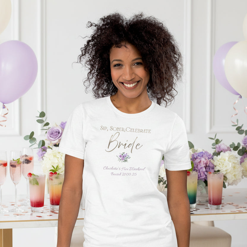 White bride t-shirt with “Sip, Sober, Celebrate” metallic-effect text and floral detail, styled for a sober hen celebration.