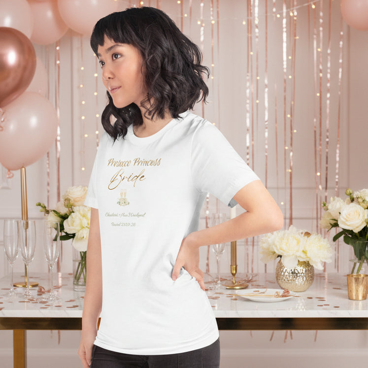 White bride t-shirt with “Prosecco Princess” metallic-effect text, floral accents and prosecco glass details for a hen party.