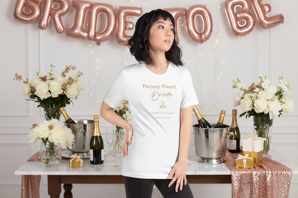 White bride t-shirt with “Prosecco Princess” metallic-effect text, floral accents and prosecco glass details for a hen party.