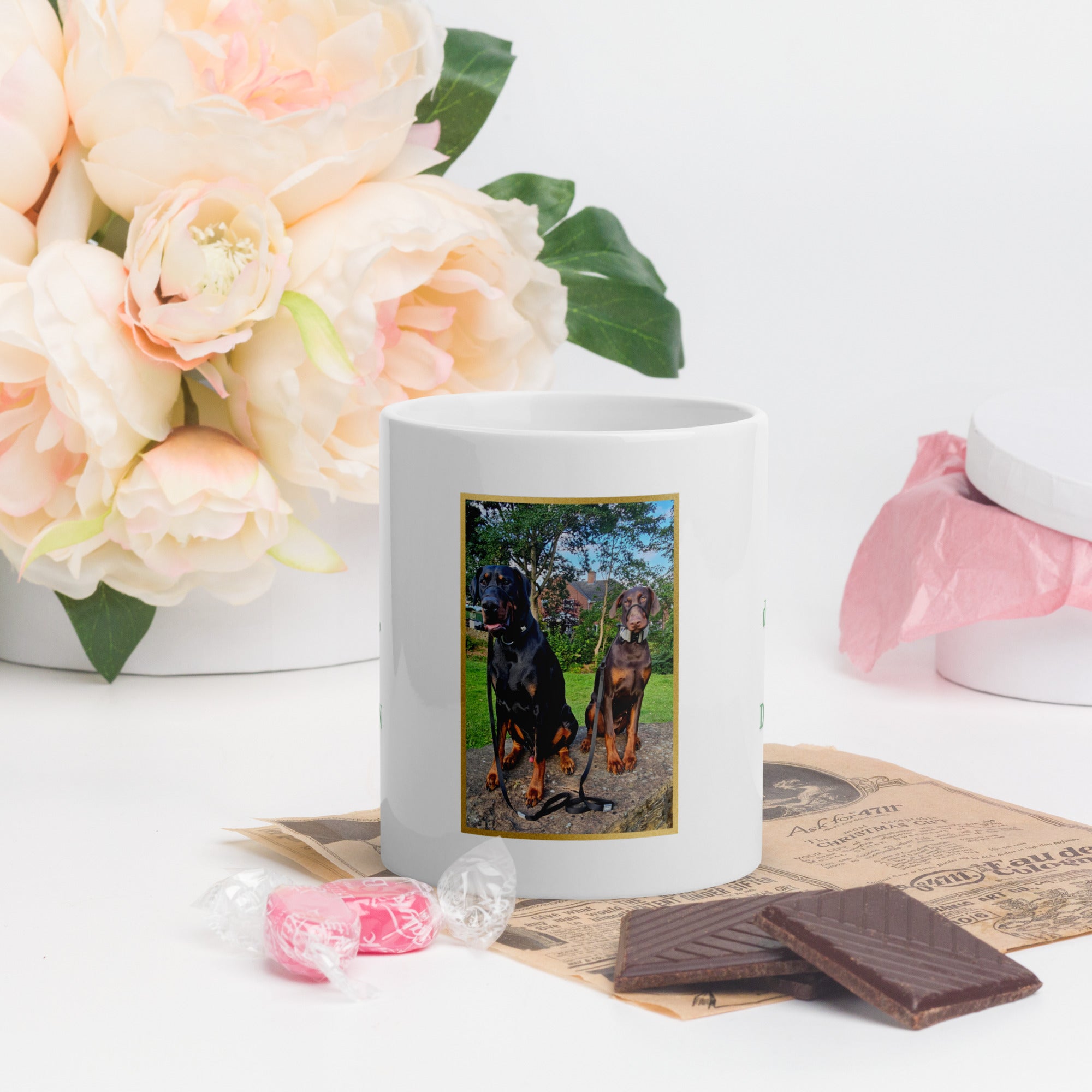 White mug with a dog design on a table with flowers and chocolates