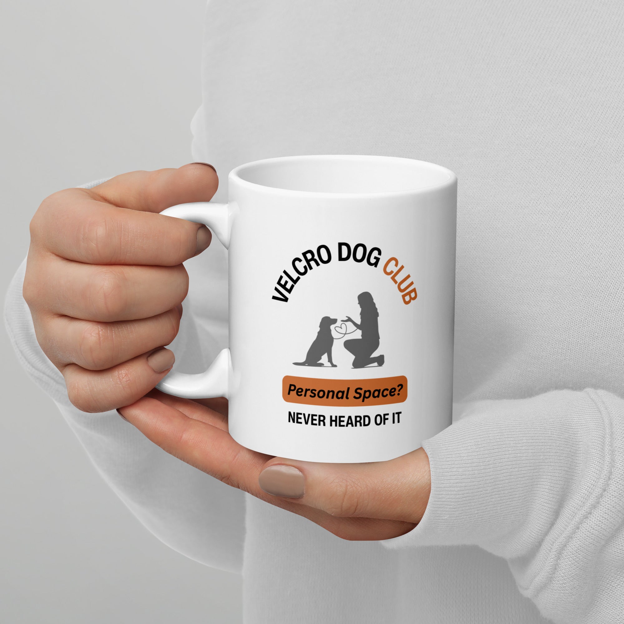 Hand holding an 11oz white mug with 'Velcro Dog Club' text and graphic on a grey background
