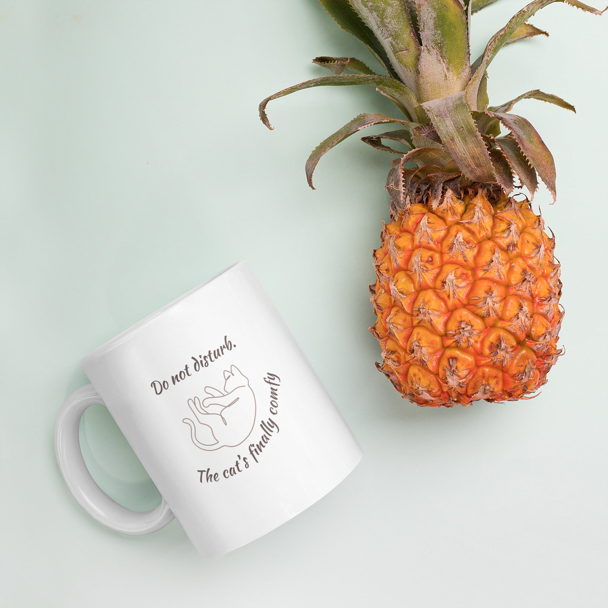 White mug with text and a pineapple on a light green background