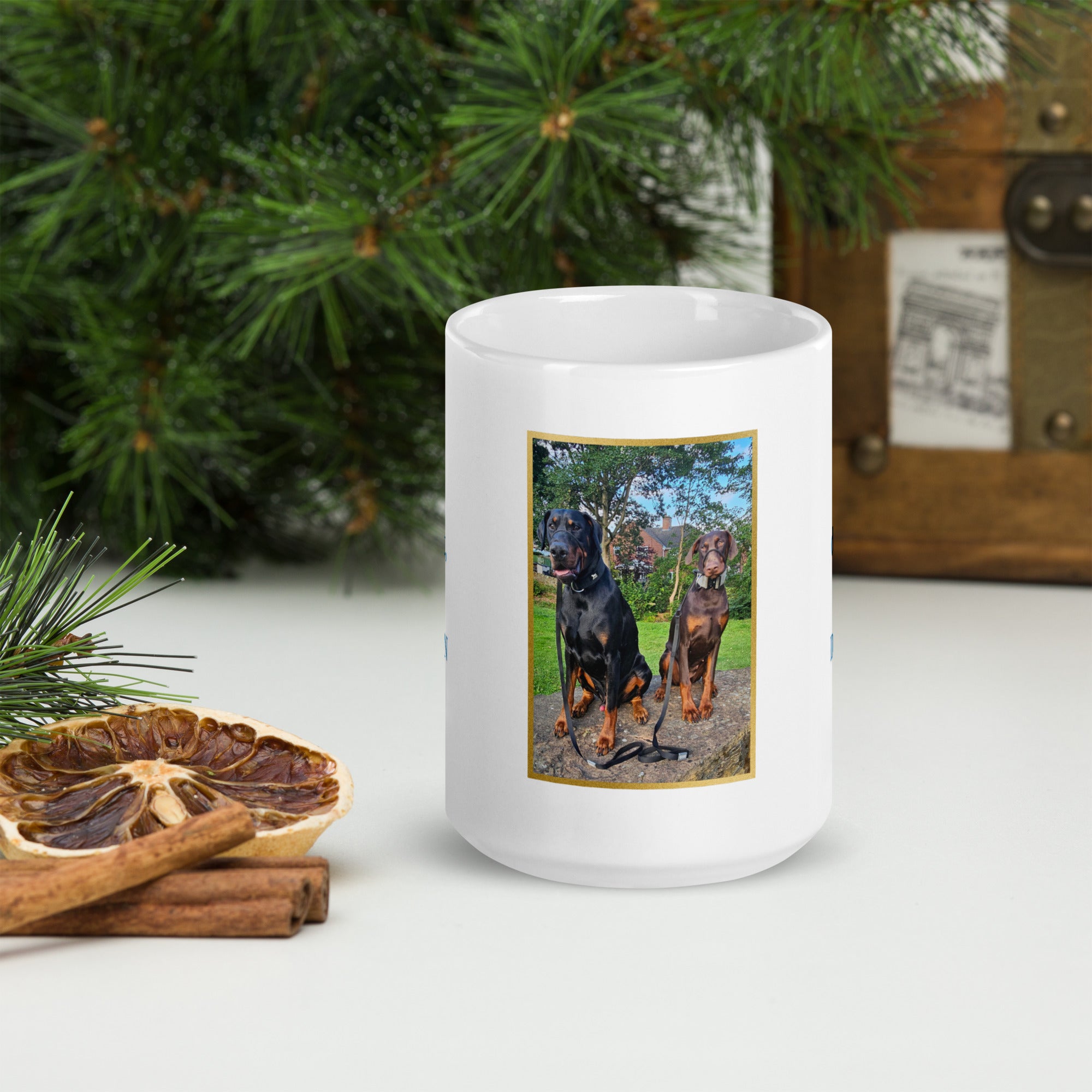 White mug with a picture of two dogs on a white surface with Christmas decorations.